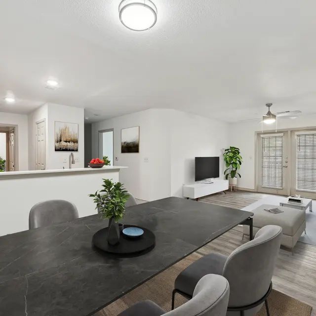 A modern dining room with a black table and grey chairs.